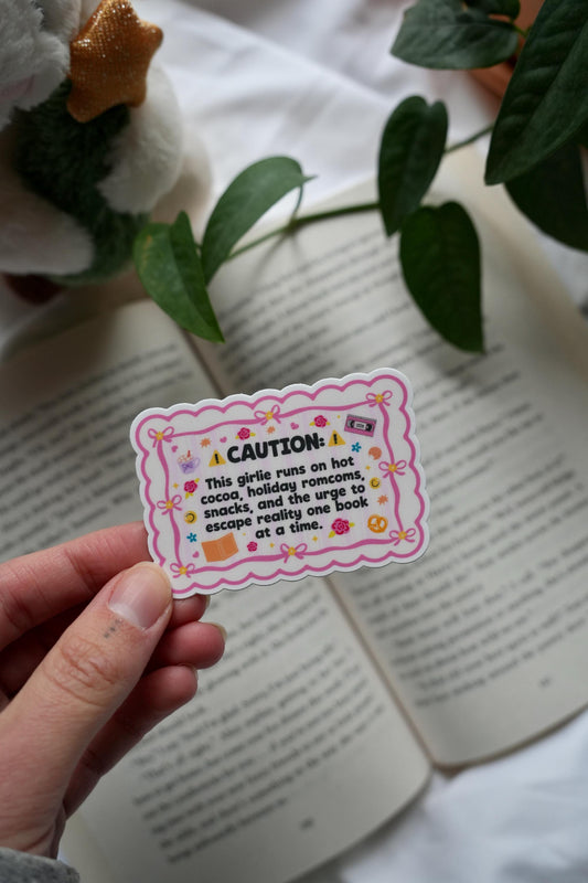 Caution: This girlie runs on hot cocoa, holiday romcoms, snacks, and the urge to escape reality one book at a time sticker